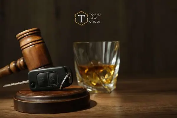 car keys and glass of whiskey beside mallet and gavel